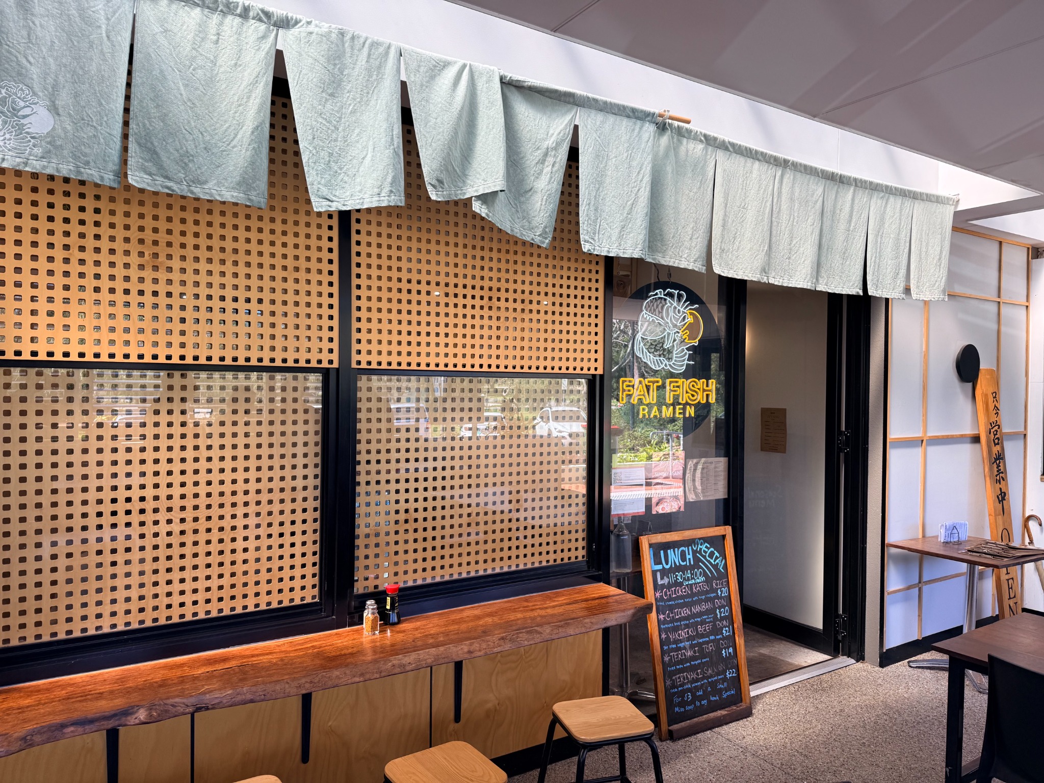 Timber counter seating beneath pale noren curtains at Fat Fish Ramen